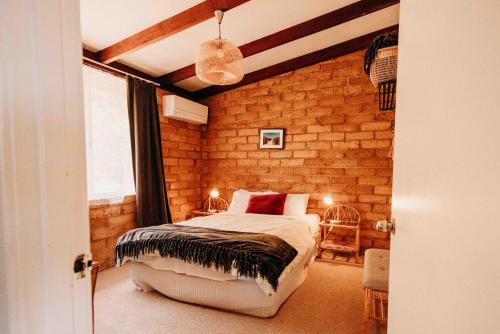 a bedroom with a bed and a brick wall at Margaret River Holiday Cottages in Margaret River Town