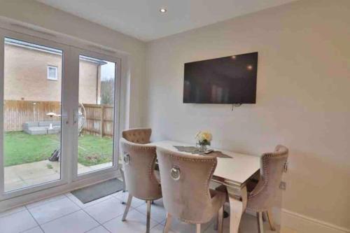 a dining room with a table and chairs and a television at Very Close to Chester City Centre! in Christleton