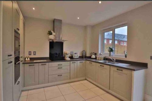 uma grande cozinha com armários brancos e uma janela em Very Close to Chester City Centre! em Christleton