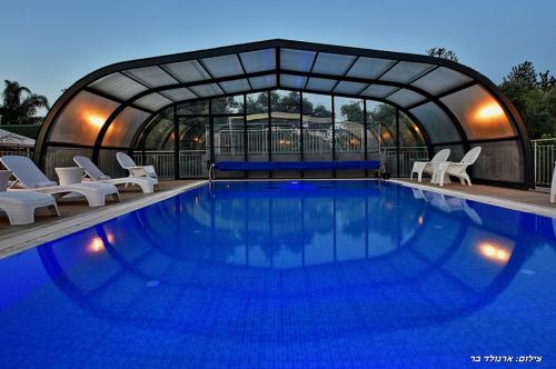 a large swimming pool with chairs and a tent at אחוזת אלכסנדר in Elifelet