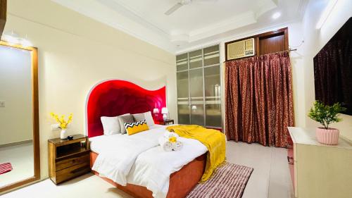 - une chambre avec un grand lit et une tête de lit rouge dans l'établissement BluO 1BHK Green Park - Balcony, Lift, Parking, à New Delhi