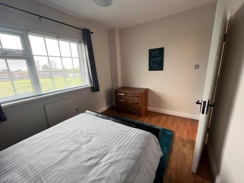 a bedroom with a bed and a window and a dresser at Enniscrone - AitEabha Country Cottage in Enniscrone