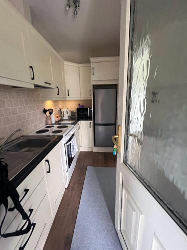 a kitchen with white cabinets and a sink and a door at Enniscrone - AitEabha Country Cottage in Enniscrone