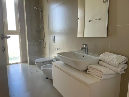 a white bathroom with a sink and a toilet at Villa 60 b - Palasë in Palasë