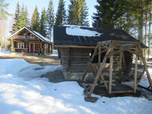 a log cabin in the snow with a swing at Mäkitorppa in Varpaisjärvi