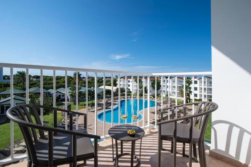 a balcony with chairs and a swimming pool at Pierre & Vacances Menorca Cala Blanes in Cala en Blanes