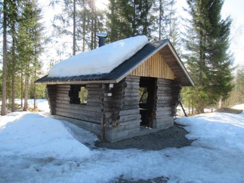 a small log cabin with snow on the roof at Mäkitorppa in Varpaisjärvi