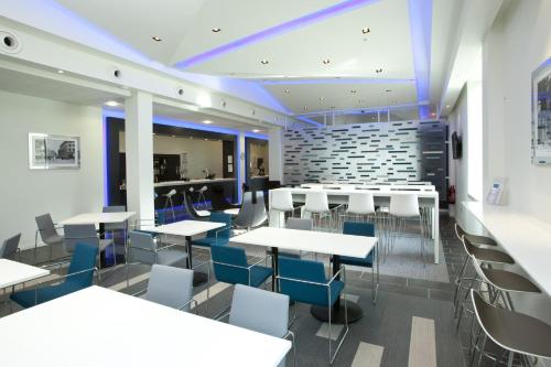 a dining room with white tables and blue chairs at Holiday Inn Express Manchester City Centre Arena by IHG in Manchester