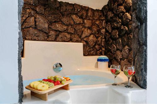 a bath tub with wine glasses and a tray of food at aletrivillas in Éxo Goniá