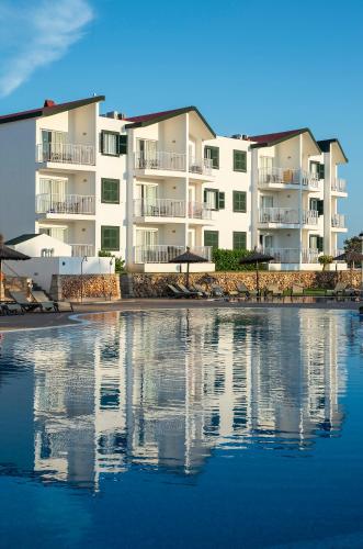 a large apartment building next to a body of water at Pierre & Vacances Menorca Cala Blanes in Cala en Blanes