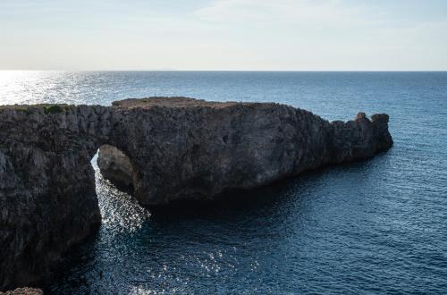 a large rock formation in the middle of the ocean at Pierre & Vacances Menorca Cala Blanes in Cala en Blanes