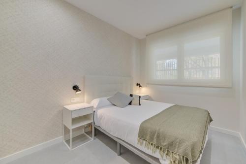 パンプローナにあるApartamentos Pamplona Confort by Clabaoの白いベッドルーム(ベッド1台、窓付)