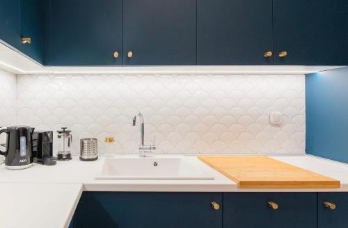 a kitchen with a white sink and blue cabinets at #White Lotus by halu! Apartments in Thessaloniki