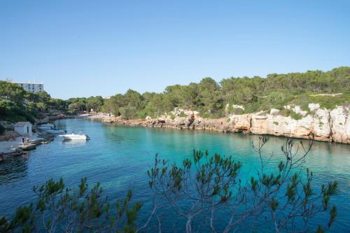 a river with boats in the water and rocks at Pierre & Vacances Menorca Cala Blanes in Cala en Blanes
