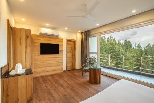 - une chambre avec une télévision et une grande fenêtre dans l'établissement Country Inn Premier Pacific Mall Road Mussoorie, à Mussoorie