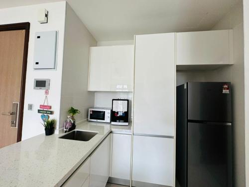 a kitchen with white cabinets and a black refrigerator at Paragon Residence 8-12pax-Big Balcony with BBQ in Johor Bahru