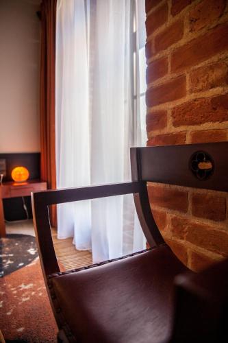 a chair in front of a brick wall with a window at Hotel Krasicki in Lidzbark Warmiński