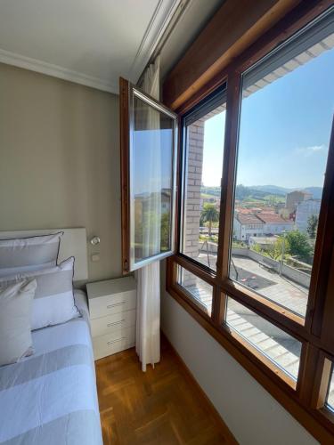 - une chambre avec un lit et une grande fenêtre dans l'établissement Apartamento Cueto, à Soto del Barco