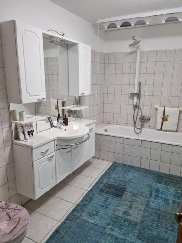 a white bathroom with a sink and a tub and a mirror at Ferienwohnung Editha mit Wintergarten in Katzow