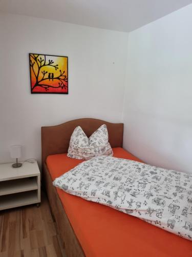 a bedroom with an orange bed and a picture on the wall at Ferienwohnung Editha mit Wintergarten in Katzow