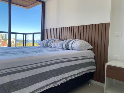 Schlafzimmer mit einem Bett und einem großen Fenster in der Unterkunft Studio 1quarto Vista Mar Barra in Salvador