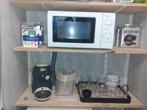 a microwave sitting on top of a shelf with glasses at Chez Flo&Fred in Barbery