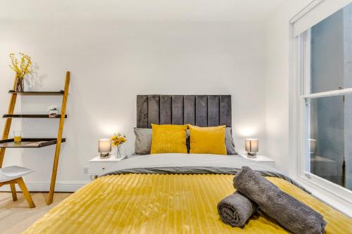 um quarto com uma cama grande e almofadas amarelas em Mews In Marylebone - Prime Central London em Londres