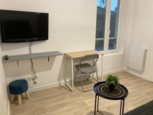 ein Wohnzimmer mit einem Schreibtisch und einem TV an der Wand in der Unterkunft 99 BIS FP in Limoges