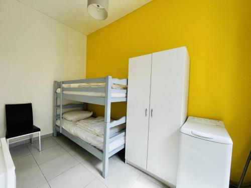 Cette petite chambre dispose de lits superposés et d'un mur jaune. dans l'établissement Élégante maisonnette à 230m de la plage avec terrasse, clim, WiFi - idéale 5 pers., Arcachon - FR-1-433-100, à Arcachon