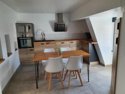 a kitchen with a wooden table and white chairs at Le Green Duplex moderne en hypercentre in Sarreguemines