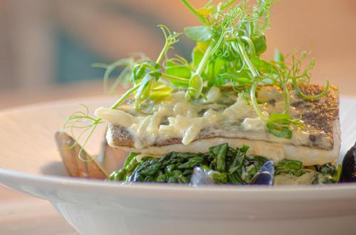 a plate of food with a piece of fish with greens at Molesworth Arms in Wadebridge
