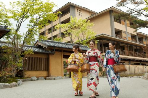 Tres mujeres en kimonos caminando frente a un edificio en Tokinoniwa, en Kusatsu