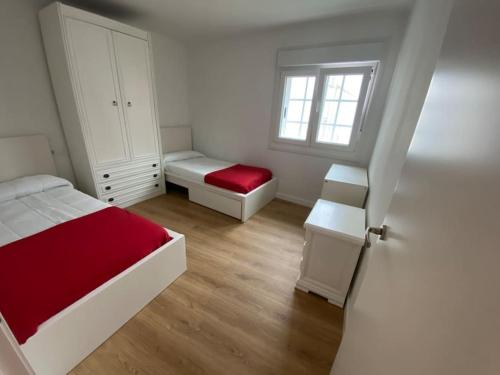 a white bedroom with a bed and a window at Céntrico piso en Portonovo in Portonovo