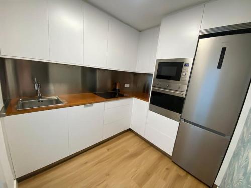 a kitchen with white cabinets and a stainless steel refrigerator at Céntrico piso en Portonovo in Portonovo