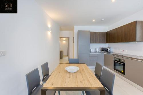a kitchen with a wooden table and some chairs at Stunning 3BR penthouse, opposite the harbour by 360 Estates in Tal-Pietà