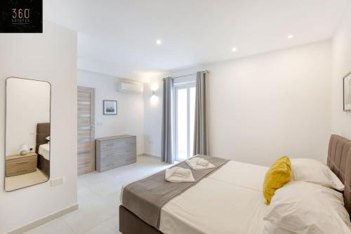 a white bedroom with a bed and a mirror at Stunning 3BR penthouse, opposite the harbour by 360 Estates in Tal-Pietà