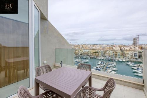 d'un balcon avec une table, des chaises et un port. dans l'établissement Stunning 3BR penthouse, opposite the harbour by 360 Estates, à Tal-Pietà