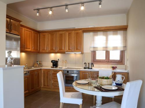 una cocina con armarios de madera, mesa y sillas en Condo in Aegina, en Aegina Town