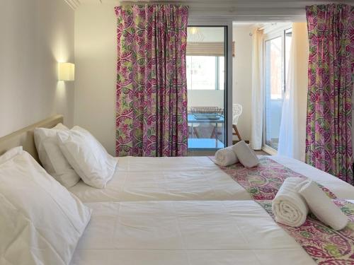 a bedroom with a large white bed with pink curtains at Sofeelings, Estudio Sol, Baixa de Albufeira in Albufeira