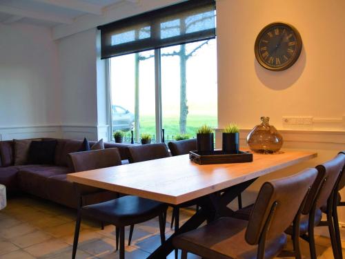 comedor con mesa y reloj en la pared en Comfortable holiday home in Schoondijke, en Schoondijke
