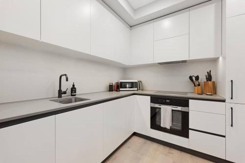 a white kitchen with white cabinets and a sink at Love Peace and Style in Melbourne
