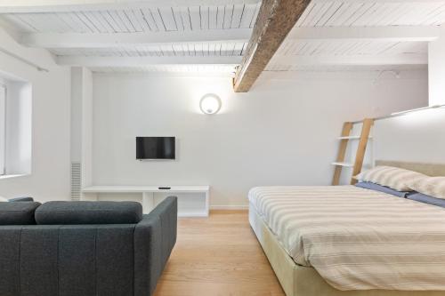a bedroom with a couch and a tv on the wall at La Corte Apartment 1 in Peschiera Borromeo