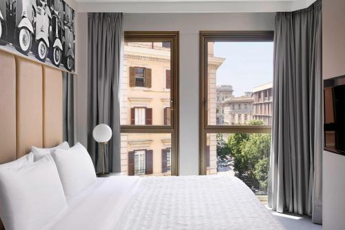 a bedroom with a white bed and a large window at Le Meridien Visconti Rome in Rome