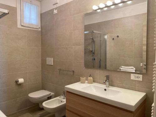 een badkamer met een wastafel, een toilet en een spiegel bij Flowers and garden apartment in Manerba del Garda