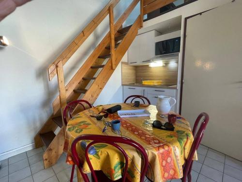 une table de salle à manger avec une nappe jaune et un escalier dans l'établissement Maison 2 pièces avec mezzanine, terrasse et parking - Proche plage, Argelès-sur-Mer - FR-1-225-682, à Argelès-sur-Mer