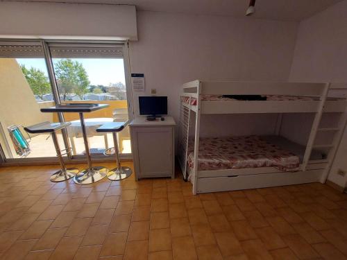 Cette chambre dispose de lits superposés et d'un bureau avec un ordinateur. dans l'établissement Studio Confortable avec Terrasse et Parking Privé, 5 Couchages, Marseillan - FR-1-326-763, à Marseillan