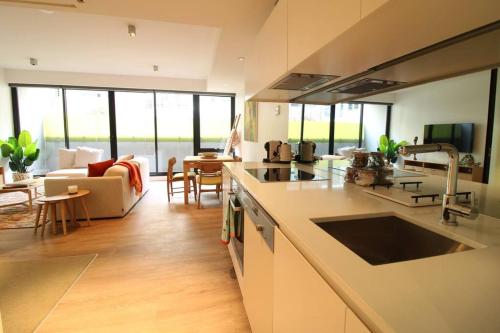 uma cozinha e sala de estar com um sofá e uma mesa em Heavenly Chic Apartment & only 30m to Bridge Road 01578 em Melbourne