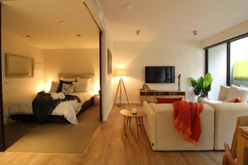 uma sala de estar com uma cama e um sofá em Heavenly Chic Apartment & only 30m to Bridge Road 01578 em Melbourne