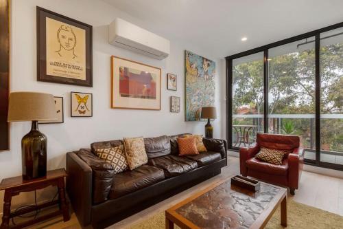 a living room with a leather couch and a table at Lovely 2 bedroom unit in North Melbourne - 03068 in Melbourne