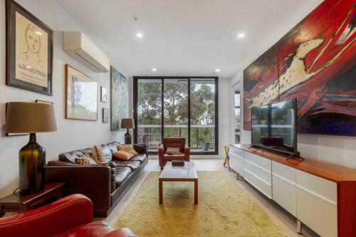 a living room with a couch and a flat screen tv at Lovely 2 bedroom unit in North Melbourne - 03068 in Melbourne